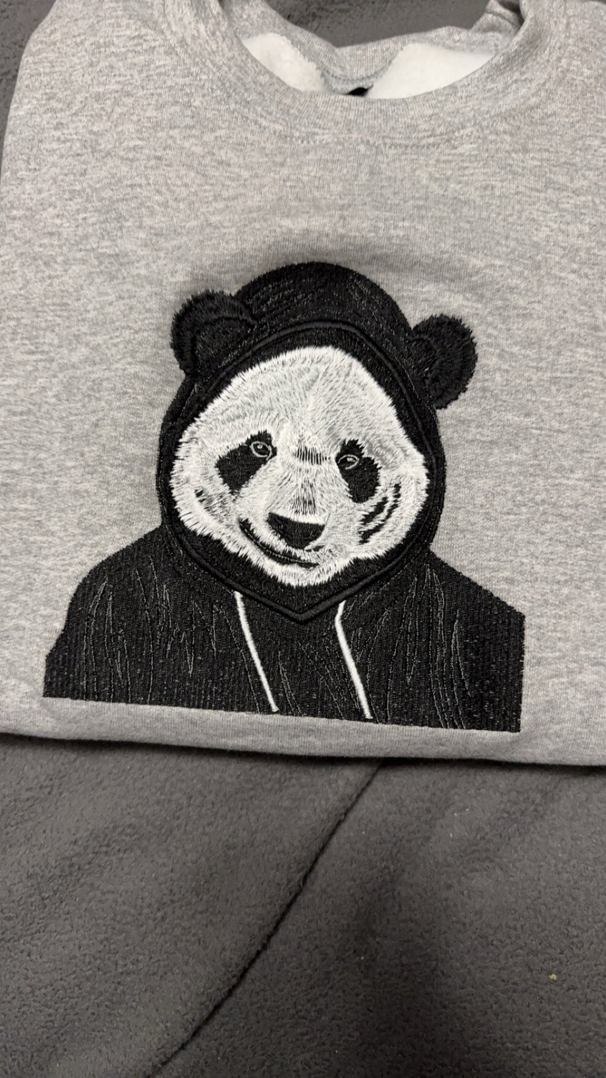 Custom embroidered gray sweatshirt featuring a detailed black-and-white panda wearing a hood, crafted by a Minnesota embroidery shop with nationwide shipping.